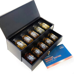 A high-end black presentation box with a pull-out drawer, open to reveal ten miniature bottles of whisky arranged in individual slots. A blue information card titled "Premium Whisky Tasting 10 Dram Gift Box" rests beside the box on a white surface.