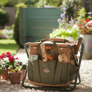 A green and tan folding garden stool with an integrated tool bag filled with a wooden-handled trowel and gardening supplies, sitting on a gravel path in a sunny garden.