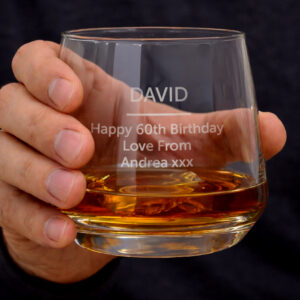 Personalised engraved whisky glass held in hand featuring custom 60th birthday message