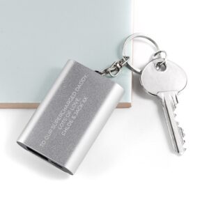 A silver rectangular emergency power bank keyring resting on a white surface next to a house key. The brushed metal surface is engraved with the message "TO OUR SUPERCHARGED DADDY, LOTS OF LOVE, CHLOE & JACK XX" in a clean, uppercase white font.