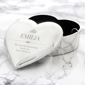 Personalised heart-shaped silver trinket box engraved with a name and message, open to reveal a delicate sterling silver necklace inside on a white marble surface.