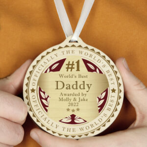A hand-held Personalised Number 1 Round Wooden Medal with a white ribbon, featuring "Officially the World's Best" engraving and custom text for "World's Best Daddy."