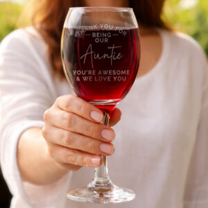 Personalised Thank You Wine Glass: A woman holding up a large wine glass filled with red wine. The glass is laser-engraved with the words "Thank You For Being Our Auntie, You're Awesome & We Love You" in a mix of modern sans-serif and elegant script fonts.