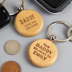 Personalised Belongs To Keyring: A high-quality metal or wooden keyring engraved with the words "This Belongs To" followed by custom names like "Daddy" or "Grandad." Shown with a sturdy silver split ring on a neutral background.