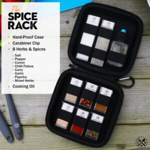 Portable Herbs and Spices Kit: A rugged black zip-up travel case called 'The Spice Rack' open on a wooden table, containing eight small refillable spice containers and a bottle of cooking oil secured by elastic straps.
