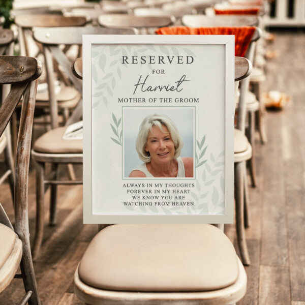 Personalised Reserved For photo upload memorial frame resting on a wooden chair at a wedding ceremony reading Reserved For Harriet Mother of the Groom.
